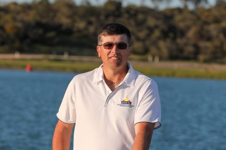 A man stands on a pier looking at the camera.