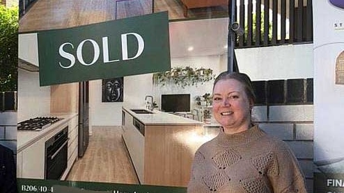 a woman in front of a sold sign out the front of an apartment block with a real estate agent