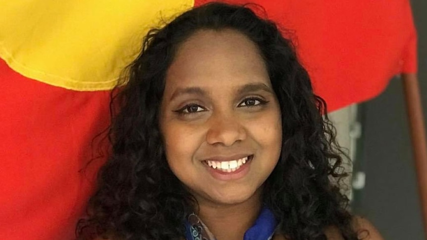 Portrait of Shailyn Isaac in front of the Australian Aboriginal flag.