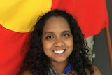 Portrait of Shailyn Isaac in front of the Australian Aboriginal flag.
