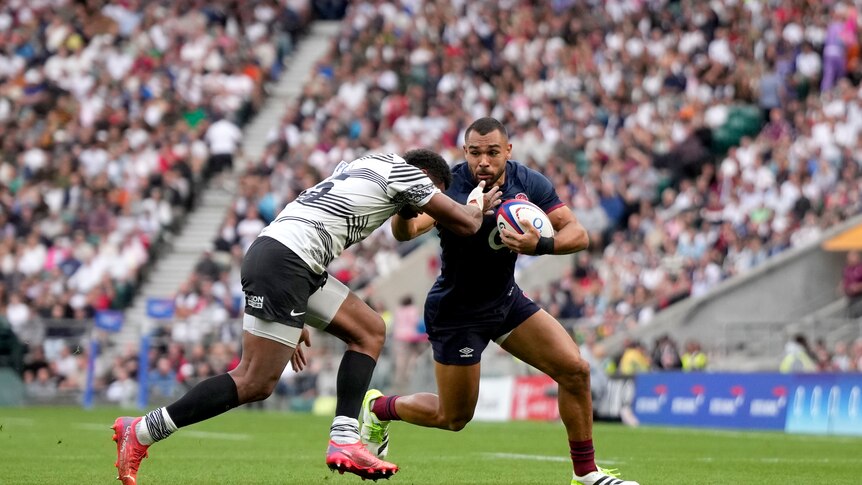 A fijian player, Islaisa Droasese attempts to tackle Englands Joe Marchant during a rugby match