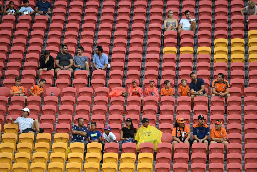 A small number of fans sit scattered amongst empty seats.