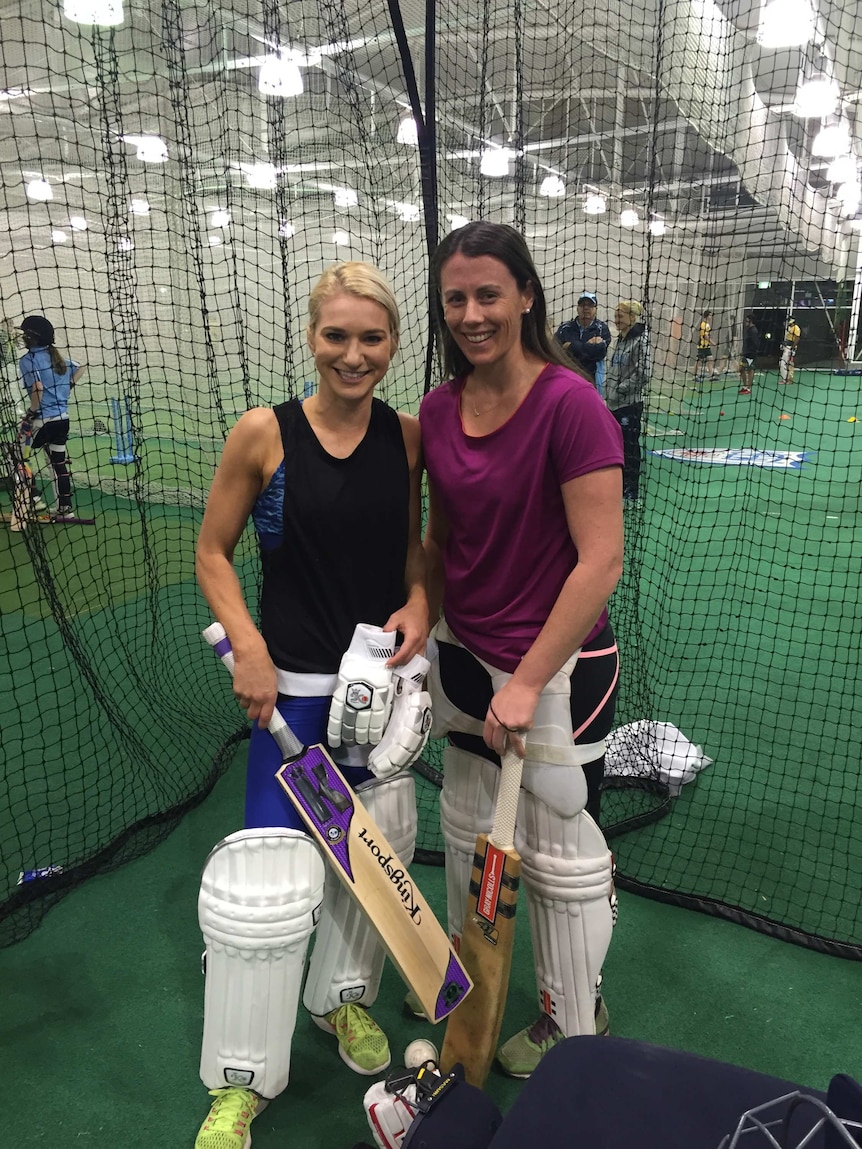 Kate Hollywood and Kym Turnell stand holding cricket gear.