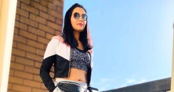 A woman smiles for the camera while wearing activewear and sunglasses