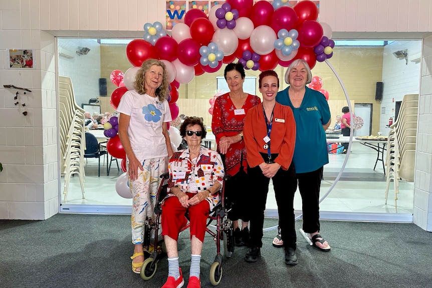 five women attending the opening of the forget me not cafe in Kalgoorlie standing under an arch of red balloons 