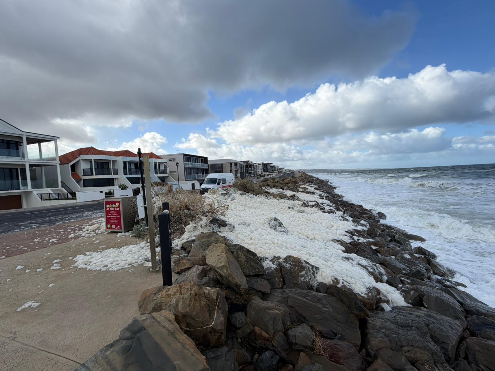 Espuma blanca sobre las rocas y se vierte sobre el pavimento, con el mar debajo