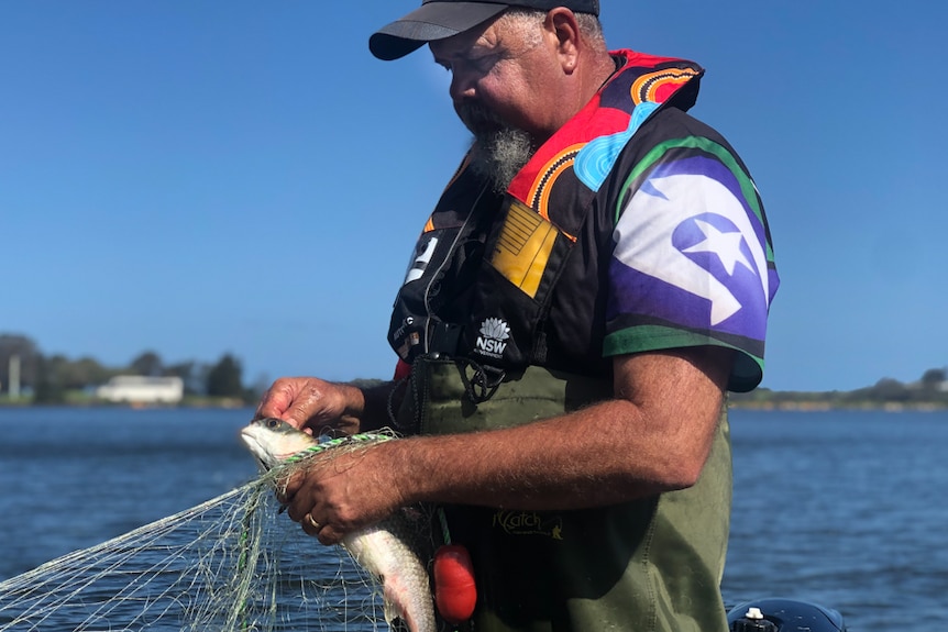 Wally Stewart standing on boat pulling a fish out of a net