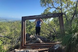 A woman standing at an outlook in front of a sign saying I took the leap