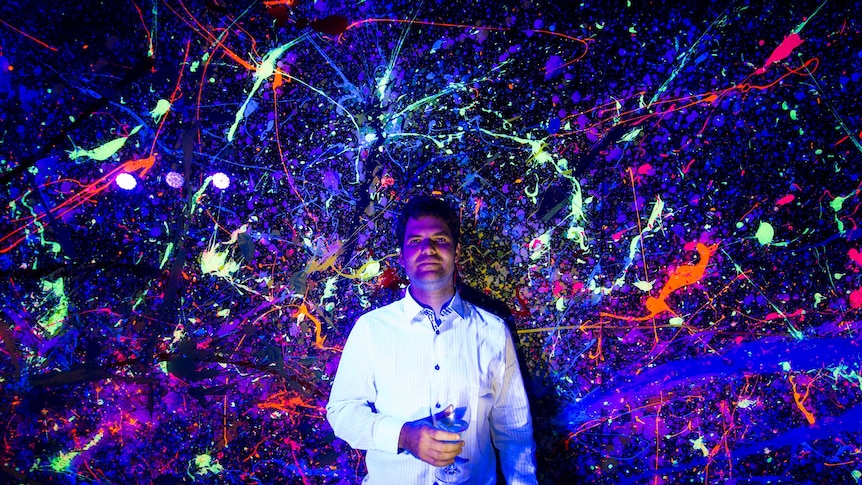 Tommy Balogh poses in front of one of his fluorescent paintings