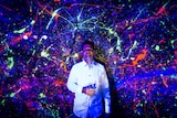 Tommy Balogh poses in front of one of his fluorescent paintings