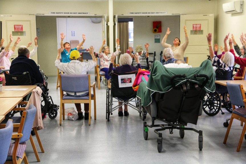 Aged care residents with hands in the air.