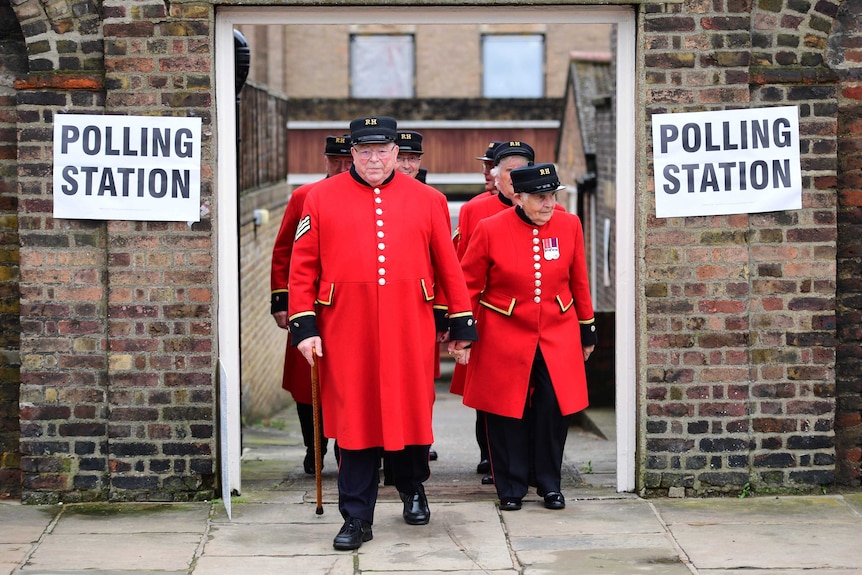 A group of Britons in red coats leave a Brexit polling station.