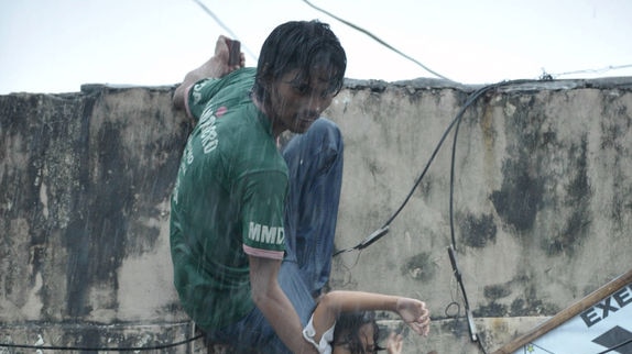 Filipino children stranded on the roof of a building escape floodwaters