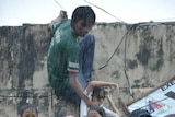 Filipino children stranded on the roof of a building escape floodwaters