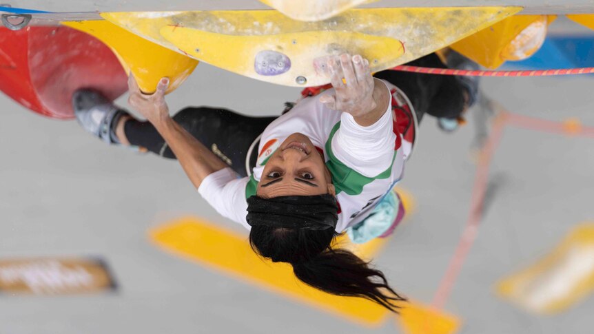 Iranian climber Elnaz Rekabi reaches for a hold during her lead climb in a competition.