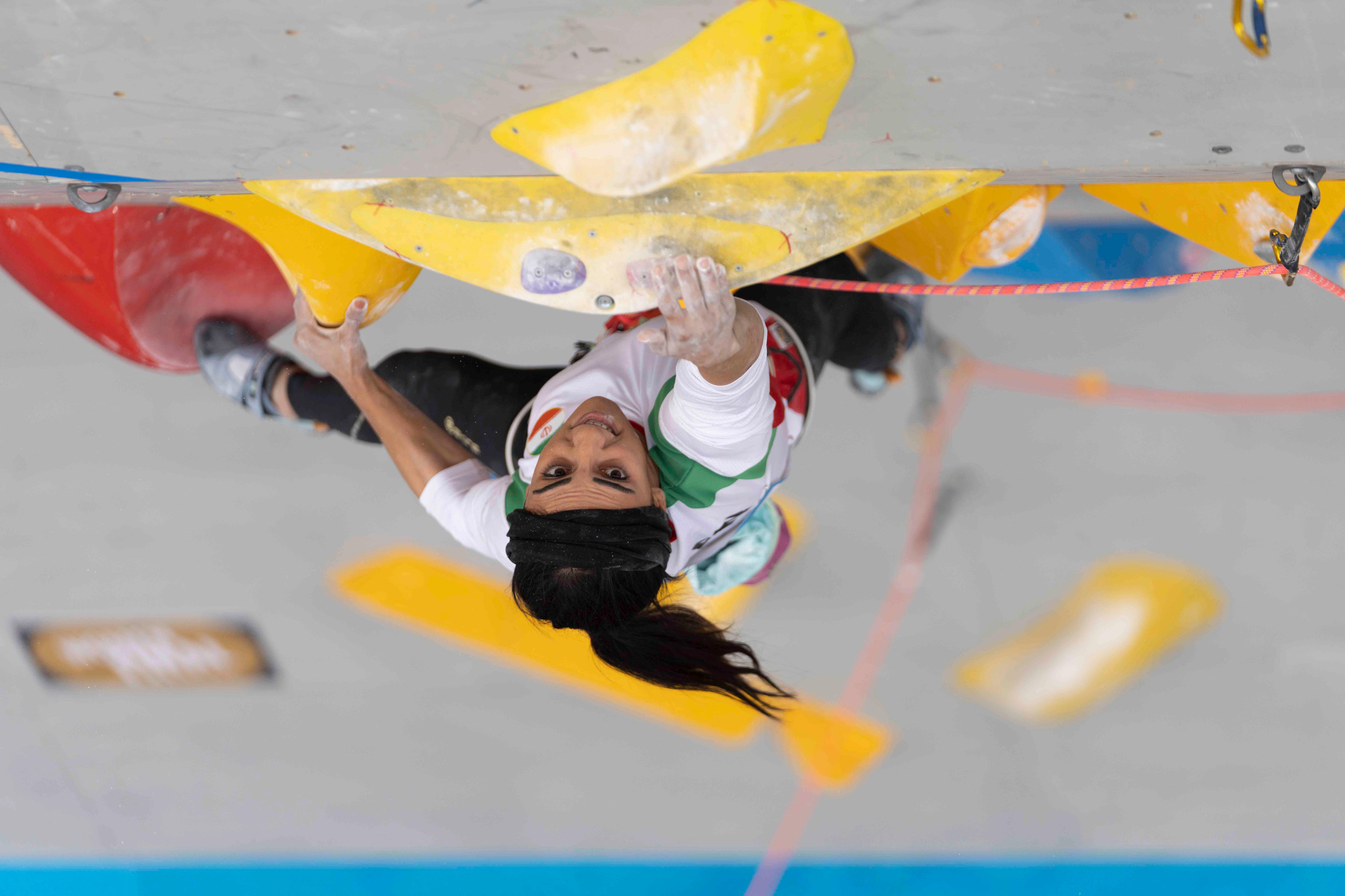 伊朗登山者 Elnaz Rekabi 在她领先的攀登比赛中伸手抓住。