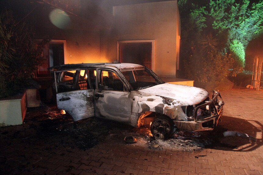 A car and surrounding buildings smoulder after they were set on fire inside the US consulate compound in Benghazi.