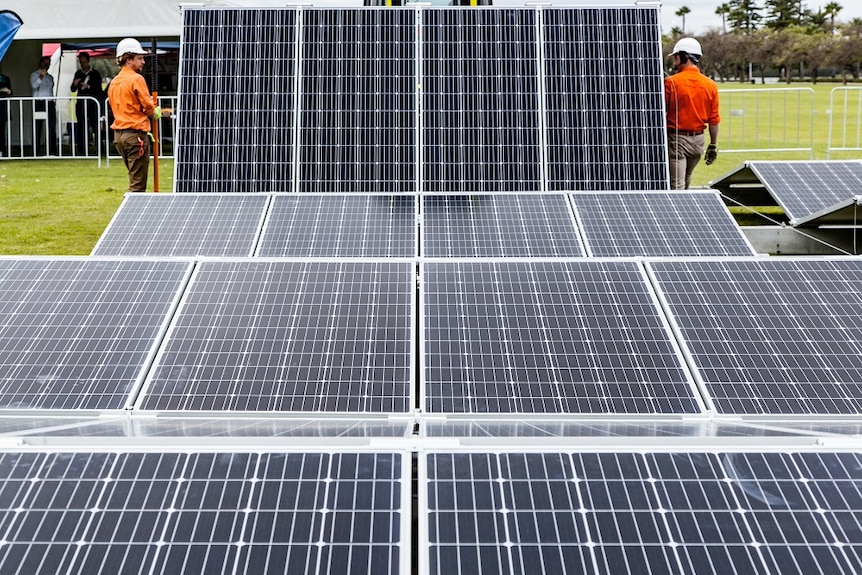 Technicians unfolding a large array of solar panels