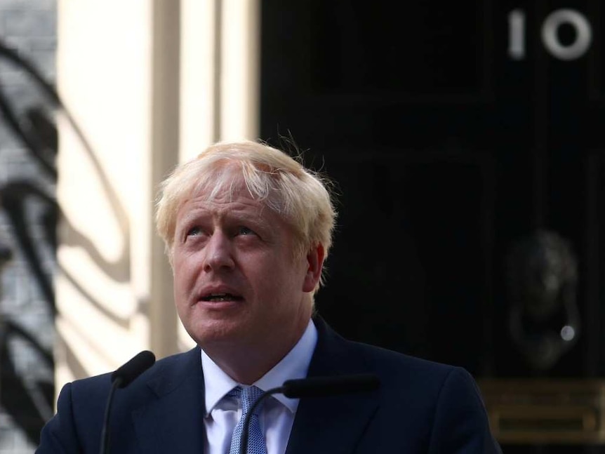 Boris Johnson behind a black lectern with the UK ensign on it in front of 10 Downing Street.