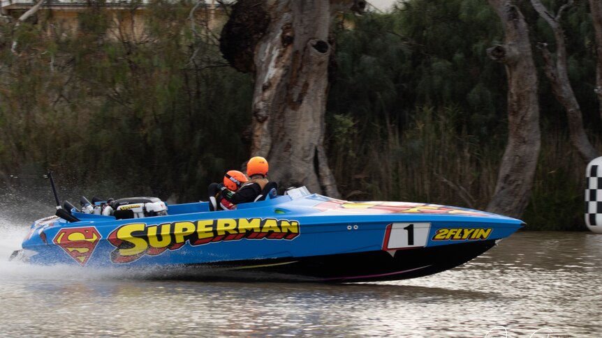 Blue ski boat racing on the Murray River with Superman logos