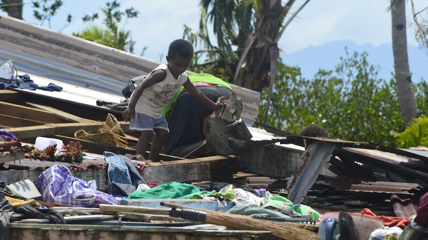 A child climbs through the remains of a home destroyed by Tropical Cyclone Winston in Fiji.