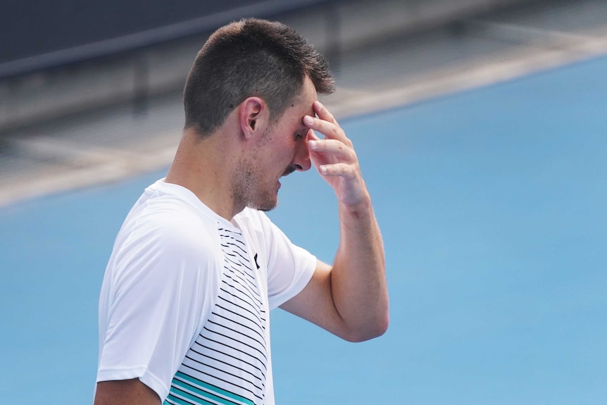 A tired tennis player runs his hand over his face during a qualifying match at the Australian Open.