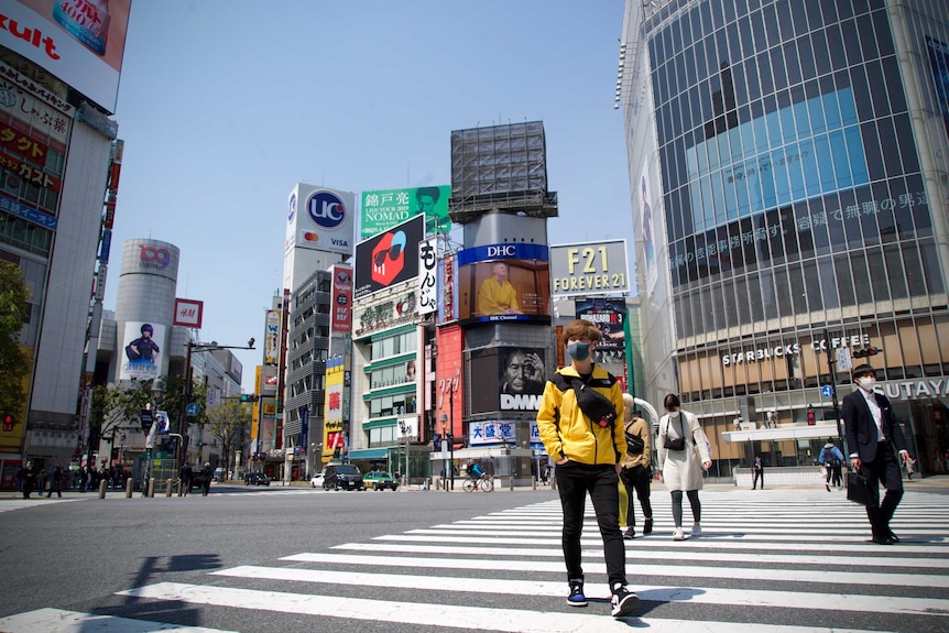 A man in face mask walks across Tokyo's Shibuya crossing