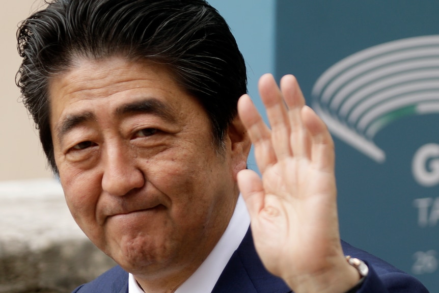 Japan Prime Minister Shinzo Abe waves outside the G7 ceremony in 2017.