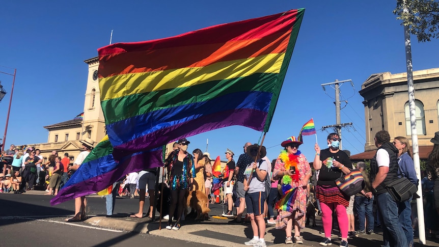 A woman holds an enormous rainbow flag