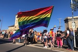 A woman holds an enormous rainbow flag