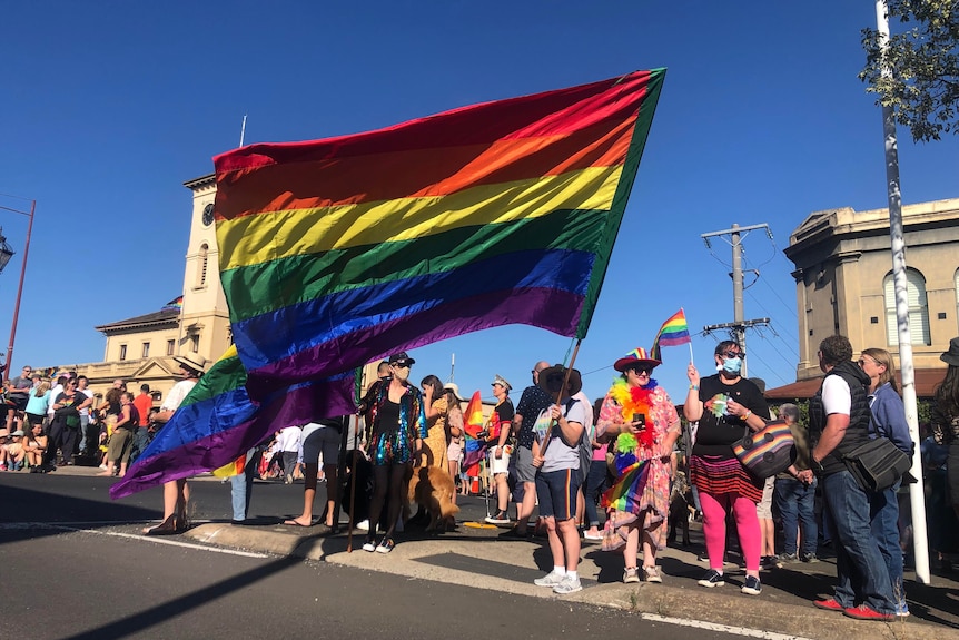 A woman holds an enormous rainbow flag