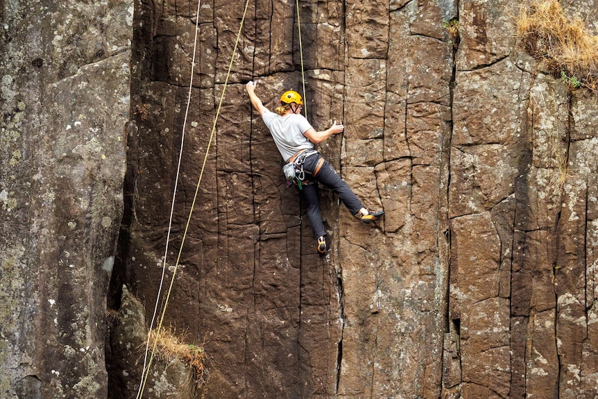 A rock climber climbing up a cliff.