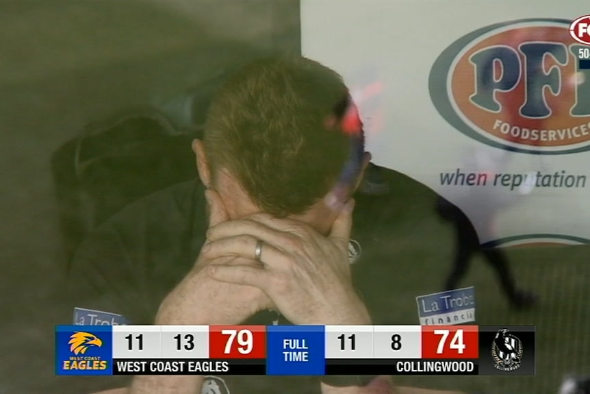 Nathan Buckley holds his head in his hands in the coach's box after the final siren of the 2018 Grand Final game.