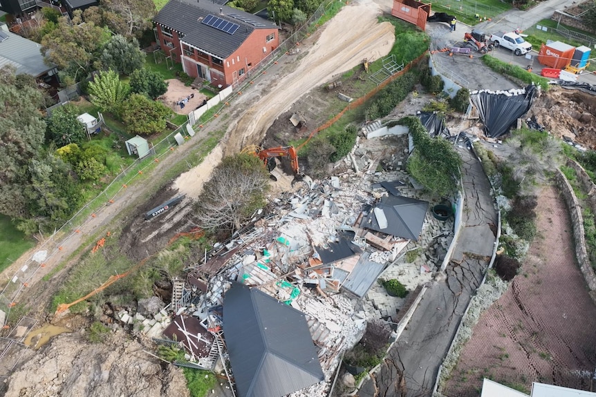 aerial view of the demolition site. A crane stands in front of a flattened home. 