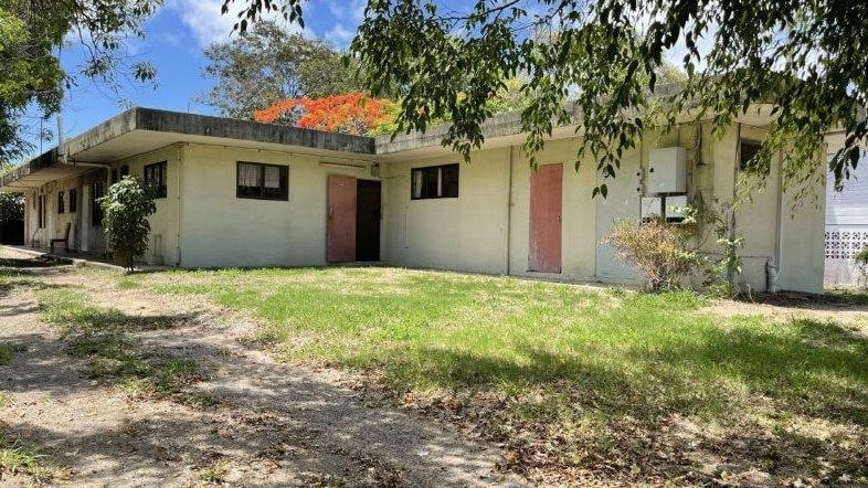 The outside of a very square home made fully on concrete with a tree in the front yard.