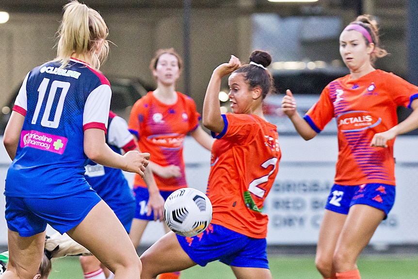 Holly McQueen shields herself from the ball, wearing an orange ball