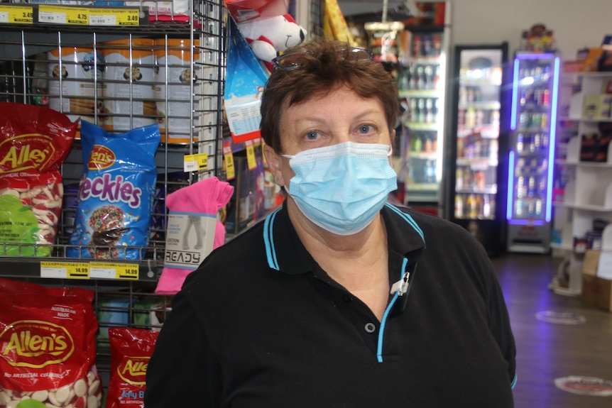 Dana standing in her supermarket, in front of a couple of bags of confectionary.