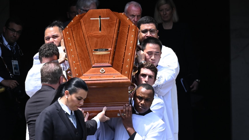 A coffin is carried outside of a cathedral