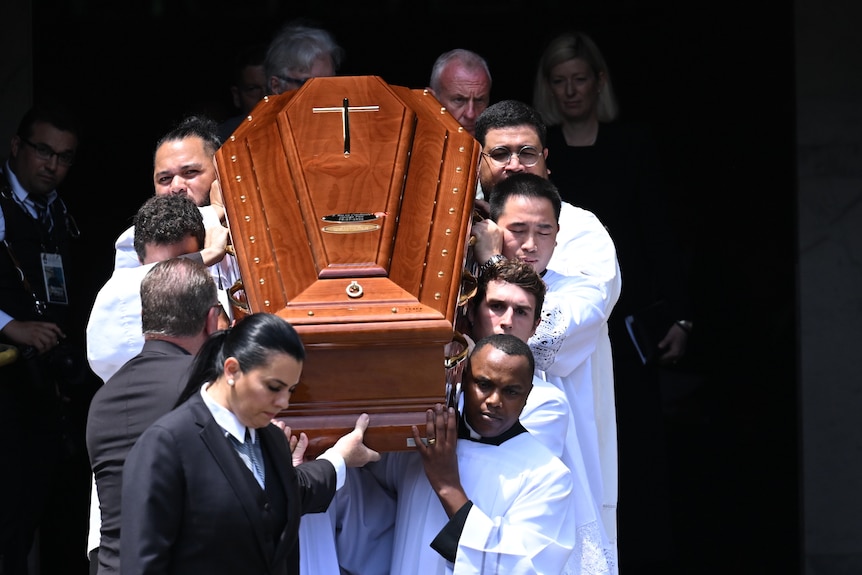 A coffin is carried outside of a cathedral