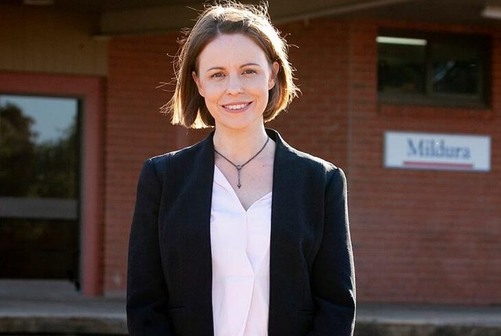 A young, dark-haired politician stands outside smiling.