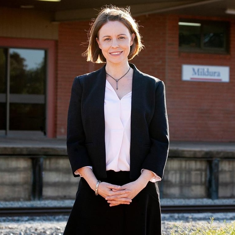 Independent candidate Ali Cupper smiles at the camera while standing in front of the platform at Mildura train station.