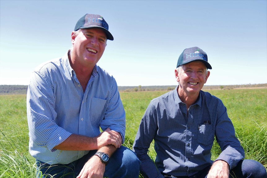 Two smiling men in a hay paddock