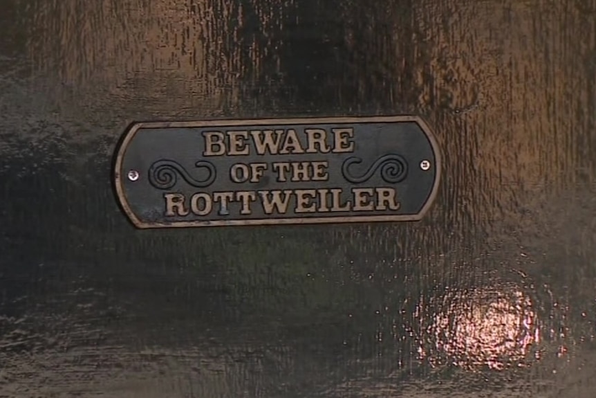 A sign states 'Beware of the Rottweiler' at the home of a woman who was attacked by her pets