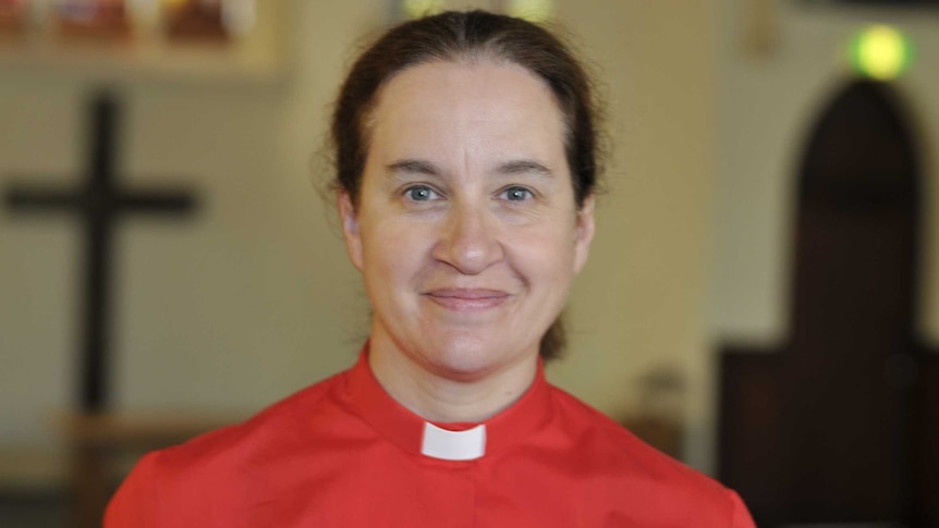 A woman wearing a red shirt with a clerical collar