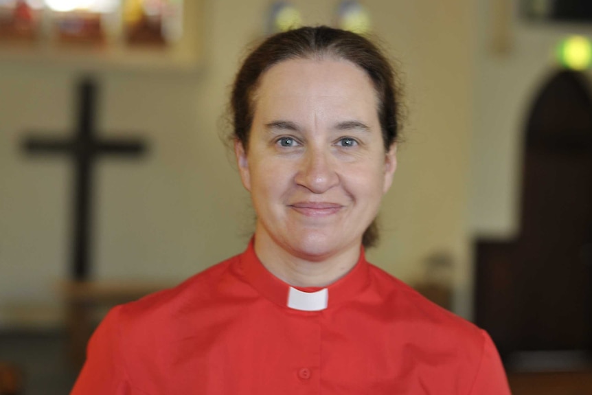 A woman wearing a red shirt with a clerical collar