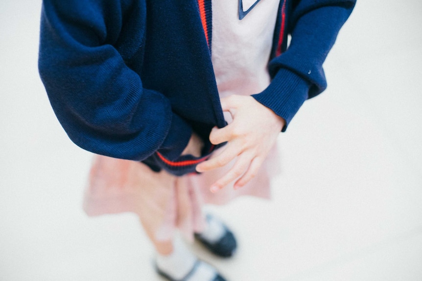 A girls puts her hand into her cardigan pocket for a story about giving kids pocket money.