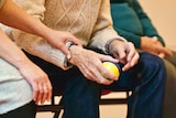 A young woman comforts an older man holding a stress ball
