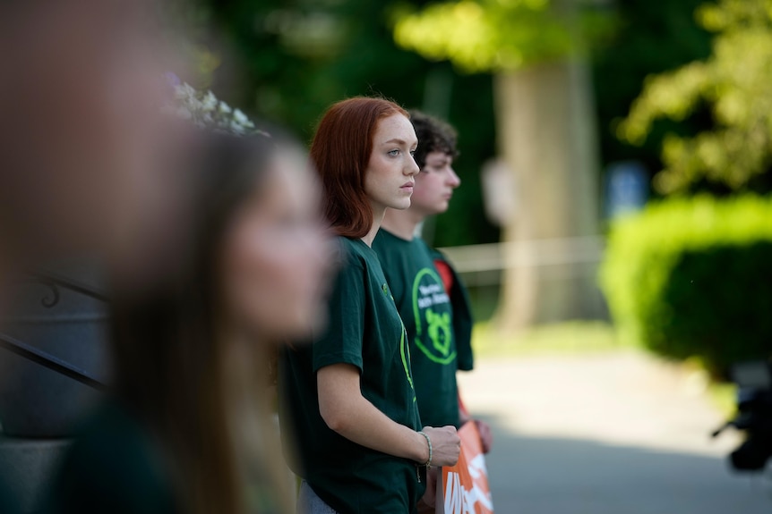 A girl with red hair wears a green shirt 