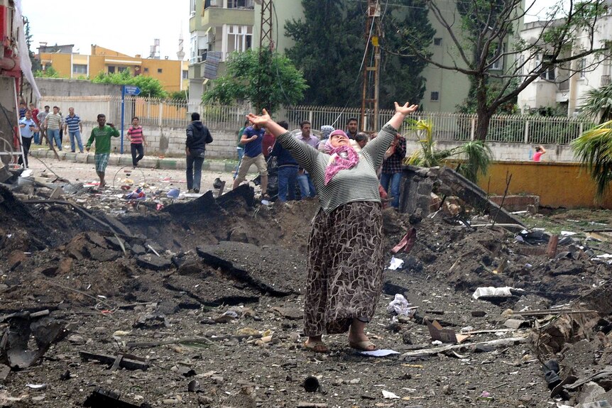 Turkish woman raises hands at the site of a car bomb blast