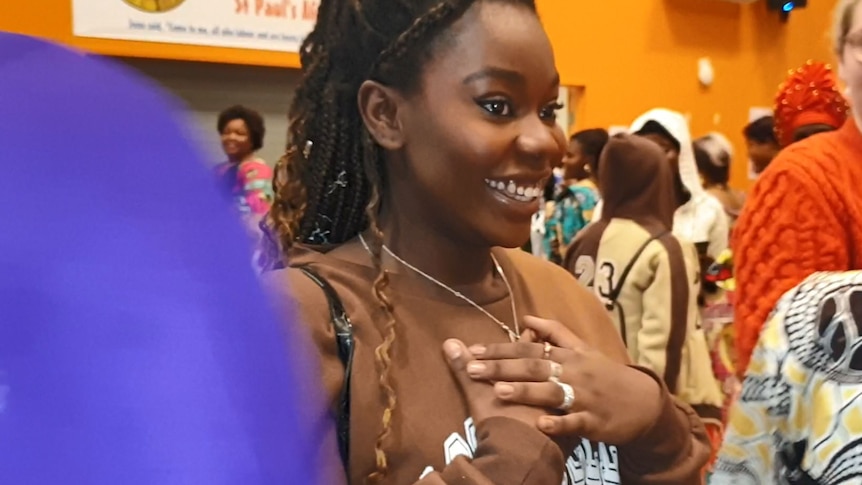 一个非洲女孩带着灿烂的微笑，高兴地把手放在胸前